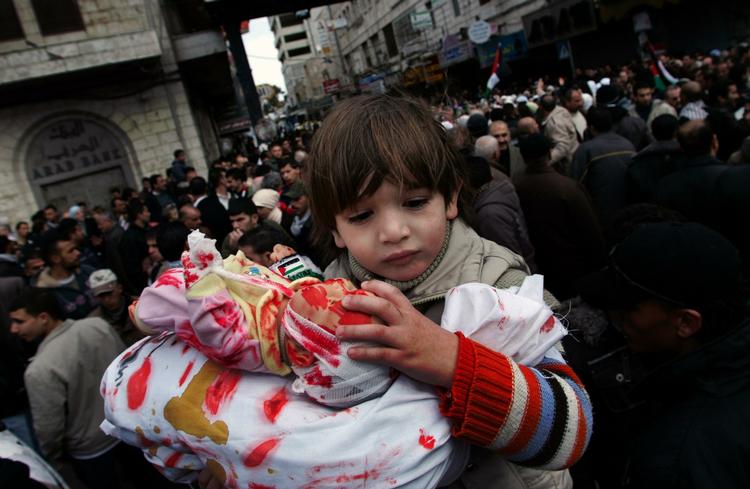 Et palæstinensisk barn på Vestbredden bruger en dukke som symbol på mange unge og børn, der er blevet dræbt i Gaza. Det skete ved en demonstration fredag. 