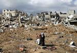 En palæstinensisk kvinde med sit barn i ruinerne i Gaza søndag eftermiddag. 