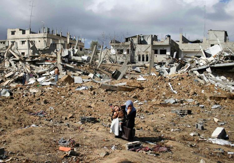 En palæstinensisk kvinde med sit barn i ruinerne i Gaza søndag eftermiddag. 
