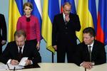 Den russiske premierminister Vladimir Putin og hans ukrainske kollega Julia Timosjenko ser til, mens cheferne for de statslige gasselskaber i går skrev den ny gasaftale under. 