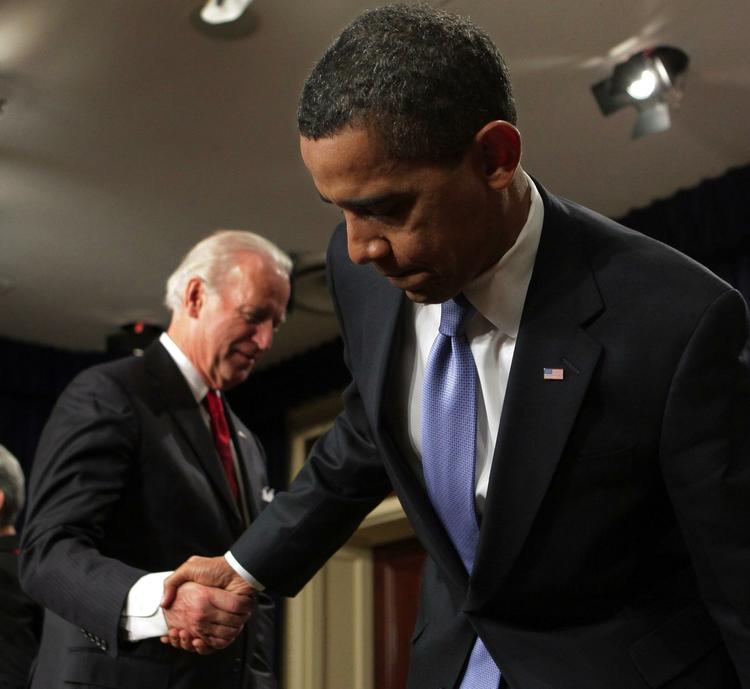 Barack Obama, forrest, trykker vicepræsident Joe Biden i hånden efter at have underskrevet en række papirer i forbindelse med sit nye virke i Det Hvide Hus. 