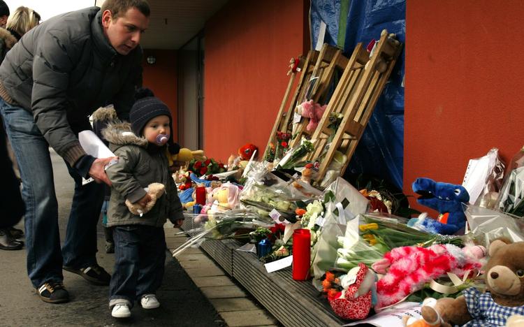 En far placerer et tøjdyr ved daginstitutionen, hvor en 20-årig mand fredag gik amok med en kniv og dræbte to små børn og en voksen. 