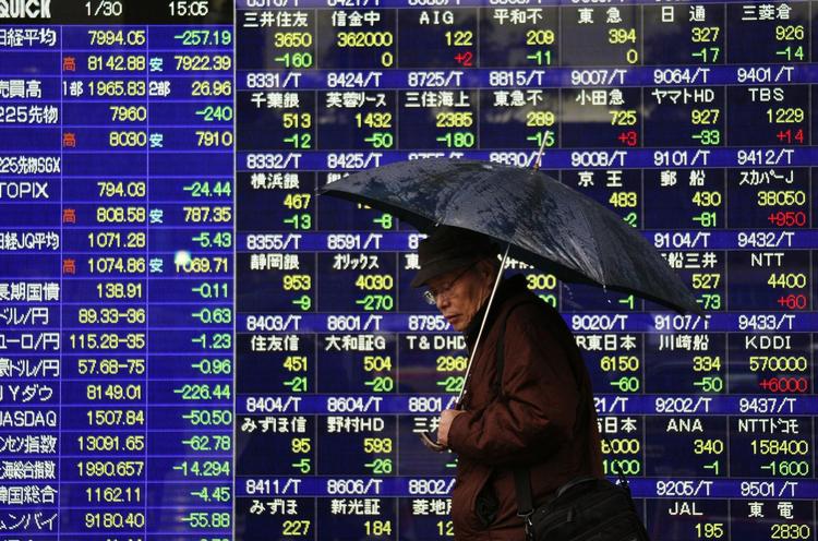 En japaner går forbi dykkende japanske aktiekurser fredag i Tokyo. 