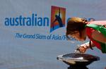 En fodgænger drikker vand foran Melbourne Park, hvor verdens tennisstjerner spiller Australien Open - trods heden! 