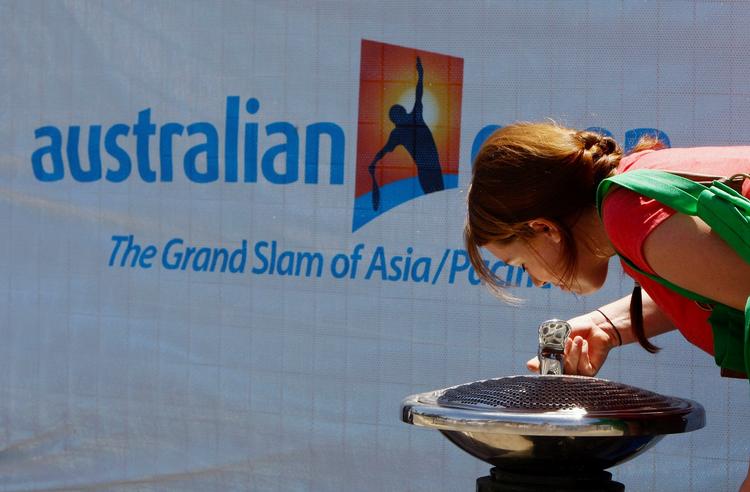 En fodgænger drikker vand foran Melbourne Park, hvor verdens tennisstjerner spiller Australien Open - trods heden! 