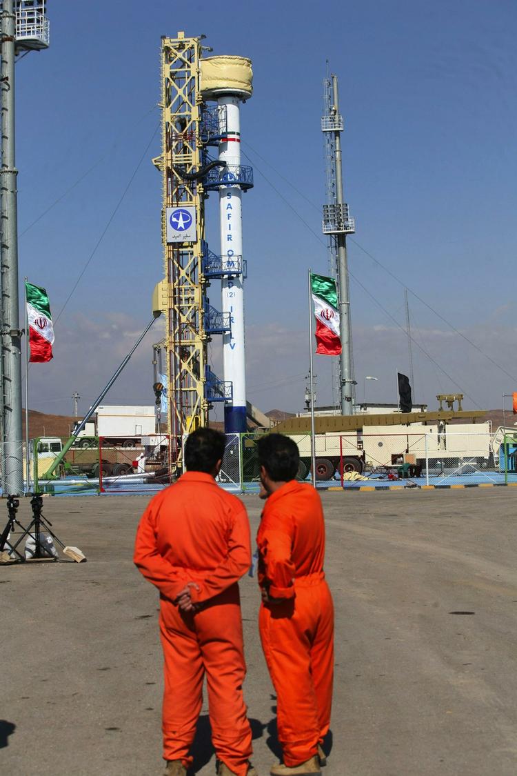 På dette billede fra det iranske Fars Nyhedsbureau betragter to mænd den raket, som mandag aften sendte en satellit i kredsløb om jorden. 