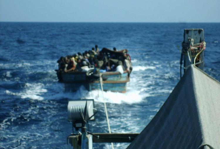 En bådfuld flygtninge fra Myanmar på slæb bag et militærfartøj langs Thailands sydvestkyst. Billedet er en del af det bevismateriale, som CNN tidligere på måneden fremlagde, og som har ført til en efterforskning af sagen hos de thailandske myndigheder. 