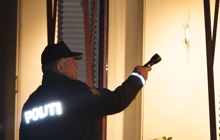 Betjent under skudhul i forretningsvindue på Rosenørns Allé. 