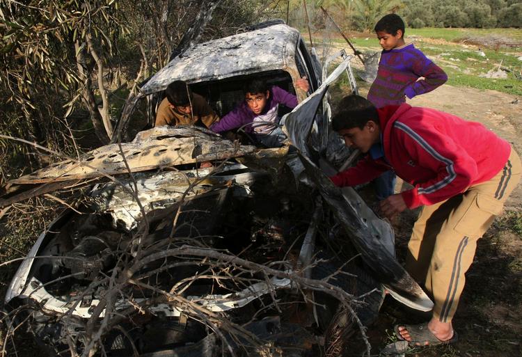 Unge palæstinensere undersøger en bil, der blev ødelagt af en israelske raket i Gaza i dag. Angrebet kom, efter at der var blevet affyret to raketter mod Israel. 