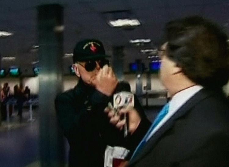 Biskop Richard Williamson knytter næven mod en journalist i lufthavnen i Buenos Aires. Biskoppen forsøgte at forsvinde fra Argentina gemt bag solbriller og kasket. 