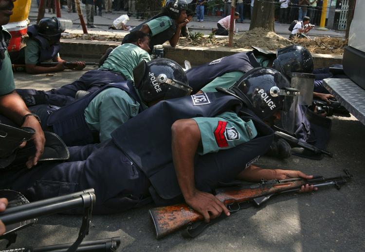 Politistyrker søger dækning udenfor de paramilitære styrkers hovedkvarter i Bangladesh' hovedstad, Dhaka. 