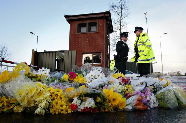 Nordirske politibetjente foran Massereene-kasernen, hvor der er lagt blomster til ære for de to dræbte ofre for lørdagens terrorangreb. 