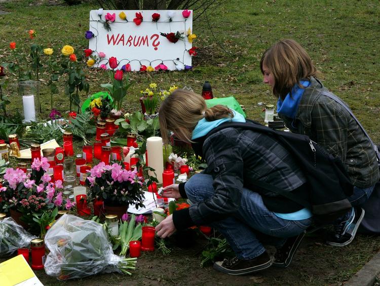 Elever og beboere i lægger blomster og stiller sterinlys ved skolen Albertville, hvor 10 elever og tre lærere blev dræbt. 