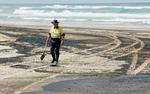 Bevæbnet med skovle forsøger indbyggerne langs de Australske strande at skovle olie-sand væk. 