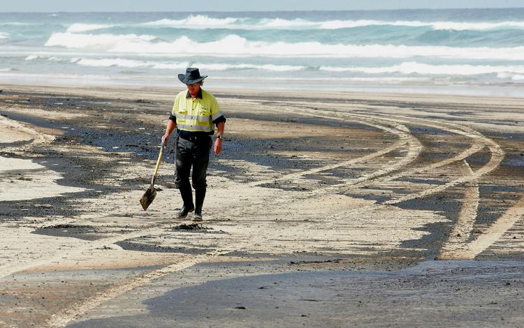Bevæbnet med skovle forsøger indbyggerne langs de Australske strande at skovle olie-sand væk. 