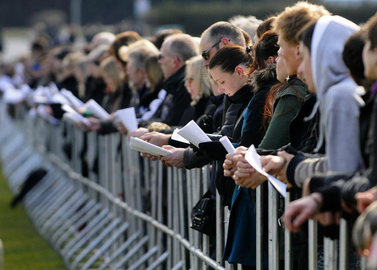 Tyskere synger, mens de overværer mindehøjtideligheden på en storskærm. 