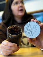 Nancy Bird med et lille glas af den olie der stadigvæk ligger tilbage på kysten. Videnskabsmænd fortæller det vil tage flere årtier før olien er væk. 