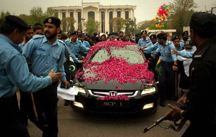 Pakistansk politi eskorterer Iftikhar Chaudrys blomstersmykkede bil. 