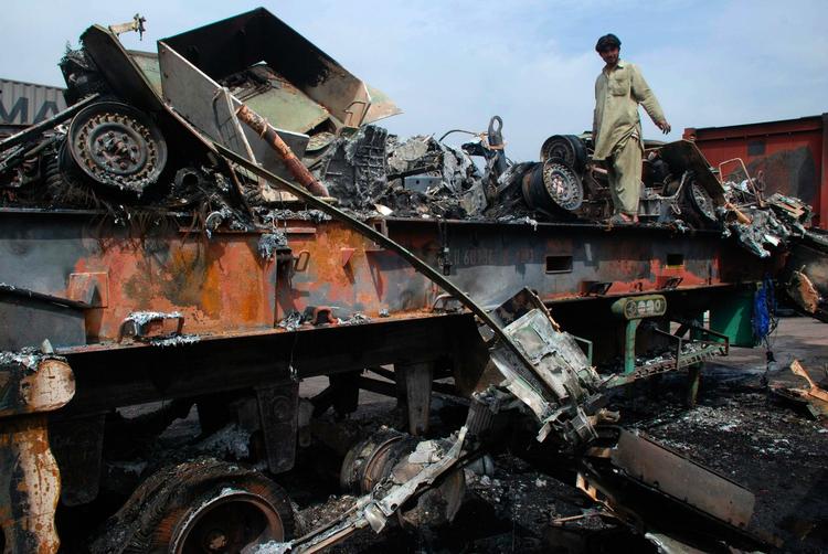 En mand betragter ved Peshawar i Pakistan de ødelæggelser mod en forsyningskonvoj, der skulle have styrket USA's tropper i grænseområdet mod Afghanistan. Arkivfoto. 