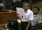Kaing Guek Eav, kendt som 'Duch', læser en erklæring op for tribunalet i Phnom Penh. Han er tiltalt for talrige grusomheder og drab. 