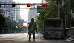 En thailandsk soldat ved en udbrændt bil dagen efter de voldsomme gadekampe i Bangkok, der kostede mindst to mennesker livet. 