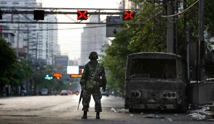 En thailandsk soldat ved en udbrændt bil dagen efter de voldsomme gadekampe i Bangkok, der kostede mindst to mennesker livet. 