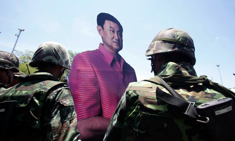 En demonstrant og tilhænger af  Thaksin Shinawatra holder en stor papfigur af Thailands afsatte premierminister, da han forlader området foran regeringsbygningen tirsdag. 
