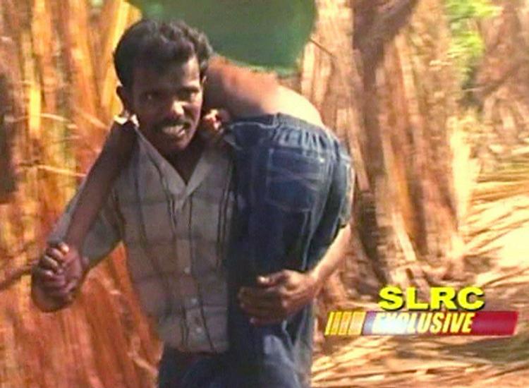 Srilankansk flygtning bærer et barn ud fra kampzonen. 