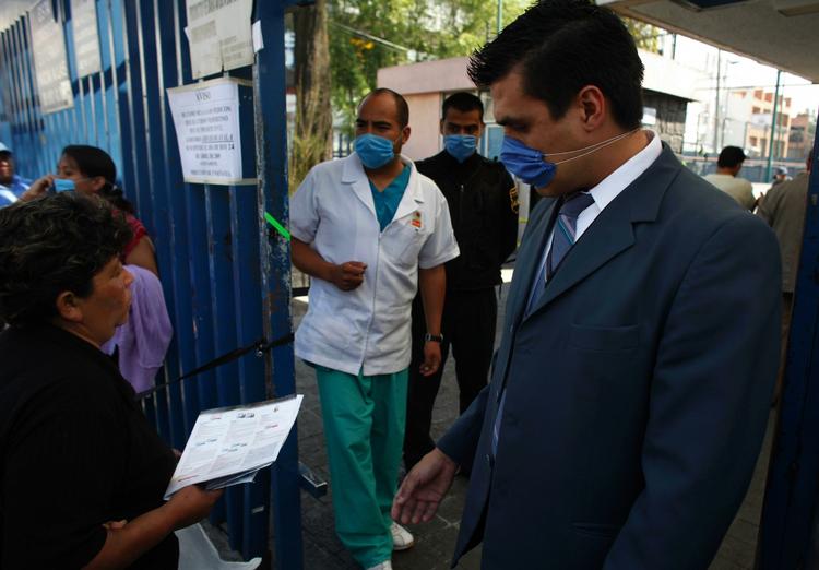 En kvinde ankommer til et hospital i Mexico City, hvor maskeklædte ansatte overvåger indgangen. 
