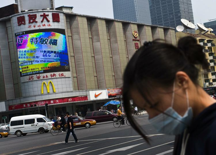 Frygten for svineinfluenza har spredt sig fra Mexico til hele verden. Her paserer en kvinde i Bejing en storskærm, som fortæller om sygdommen. 