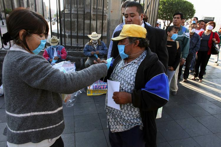 Der udleveres gratis ansigtsmasker og brochurer om svineinfluenzaen i gaderne i Mexico City. 