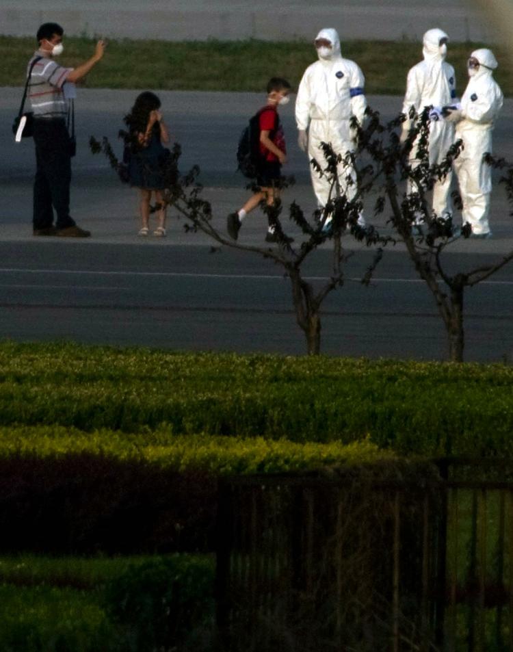 Mexicanere eskorteres ud til et ventende fly af kinesiske sundhedsarbejdere for at blive sendt til deres hjemland. 