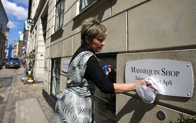 Marianne Bodét skrubber løs på skiltet til kjolebutikken i Hyskenstræde 3. Selv om graffitien er fjernet, »bliver der ligesom et lag siddende , som ikke vil forsvinde«, siger hun. 