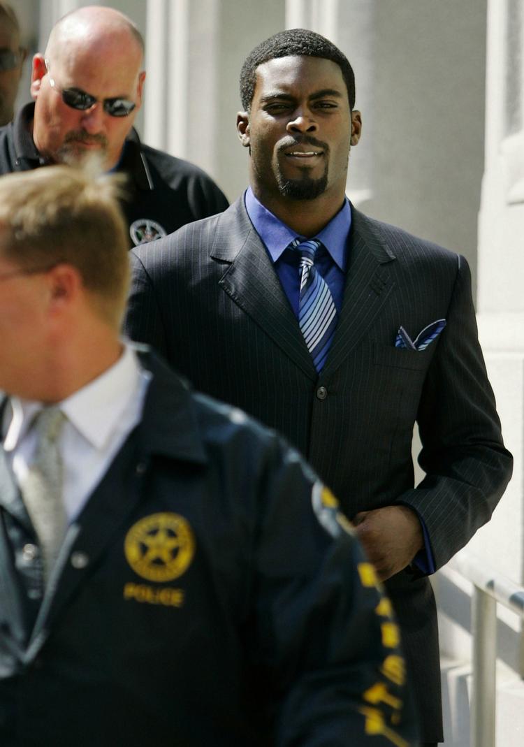 Tidligere NFL-stjerne, Michael Vick (tv) eskorteres ud af retssalen efter  at have erklæret sig skyldig i anklager om dyremishandling. Arkivfoto. 