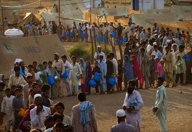 Pakistanske flygtninge står i kø for at modtage hjælp i Chota Lahore-lejren søndag. 