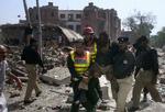 Pakistanske redningsarbejdere og politiofficerer redder en kollega ud af de ødelagte bygninger efter morgenens terroranslag. 