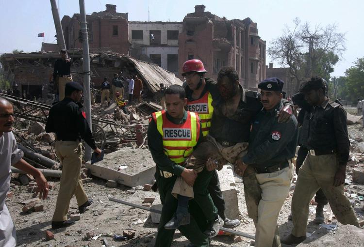 Pakistanske redningsarbejdere og politiofficerer redder en kollega ud af de ødelagte bygninger efter morgenens terroranslag. 