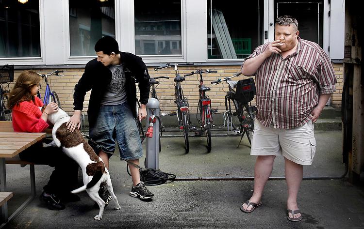 Kæresteparret Kit Madsen og Nicolas Baghdadi er ude at kigge til hunden, mens papirarbejdet inde i  Jobcenter København Skelbækgade  bliver ordnet, så de kommer ind i den  hastigt voksende kø af ungdomsarbejdsløse. Manden til højre er en ansat på jobcentret, som holder rygepause. 