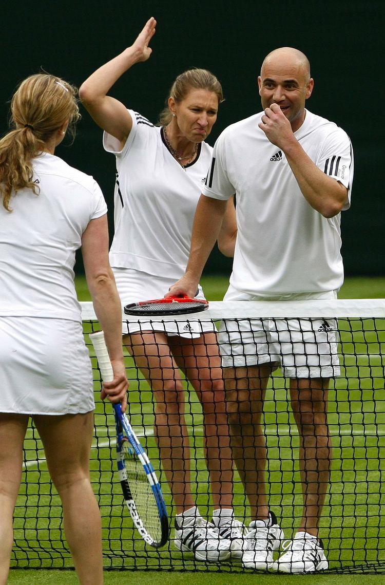Den tidligere tennisstjerne André Agassi under Roger Federer, at få den fjerde grand slam-titel i hus. Her ses Agassi (th) under en testkamp på Wimbledons græs 17. maj sammen med en anden tidligere tennisstjerne, Steffi Graf, som deler hus, hjem og barn med Agassi. Arkivfoto. 