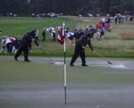 Frivillige er i gang med at fjerne vandmasserne, der har oversvømmet greens på US Open-banen. 