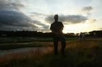 En politimand holder øje med sikkerheden for golf-stjernerne ved US Open, mens skyerne trækker sammen til regn. 