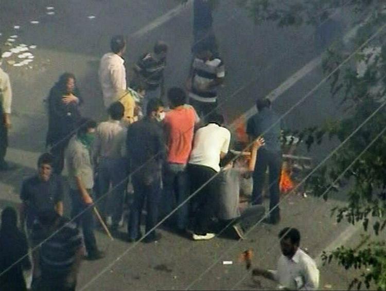 Der kommer ingen professionelle billeder ud af Iran for øjeblikket. Billedet er et amatørfoto, som er blevet sendt til AP. Billedet viser støtter af oppositionspolitiken Mir Hossein Mousavi, som sætter ild til en barrikade i den iranske hovedstad Teheran. 