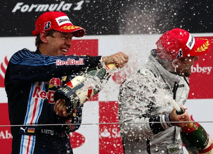 Sebastian Vettel (tv) oversprøjter løbets nummer tre, Brawns Rubens Barrichello, med champagne efter Red Bulls flotte løb i England. 