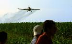 Stillbillede fra 'Bananas', der viser et fly, der sprøjter pesticider på en mark. 