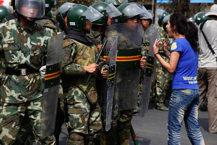 En kvinde, der tilhører minoriteren uighur, protesterer foran en gruppe soldater i Xinjiang-byen Urumqi. 