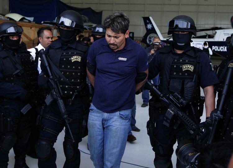 Forbundspoliti med Arnoldo Rueda Medina, et angiveligt højtstående bandemedlem i narkokartellet La Familia. Anholdelsen af Medina  førte til dødelige angreb fra narkobanden på mexicansk forbundspoliti og soldater. Ind til videre er syv døde. 