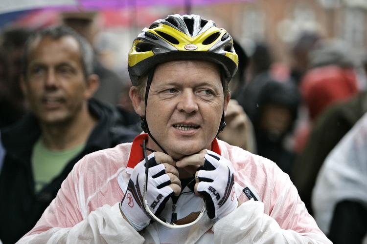 Statsministeren iført Dannebrogs-farvet cykeltøj og regnfrakke første dag af cykelturen til Paris. 