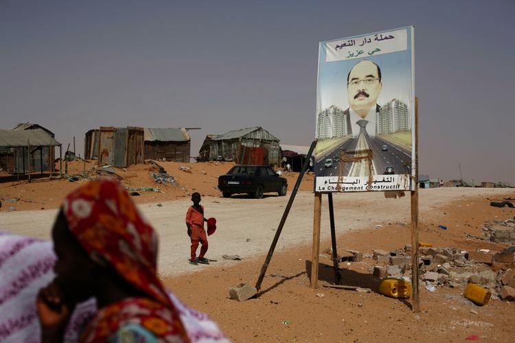 Indbyggere i kvarteret Hay Sakin i Mauretaniens hovedstad Nouakchott går forbi en valgplakat for kupgeneralen Mohamed Ould Abdel Aziz, der vandt weekendens valg. 
