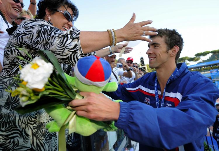 Efter præmieoverrækkelserne har Michael Phelps gjort det til en tradition at hilse på mor Debbie, der følger med på tilskuerpladserne i Rom. 