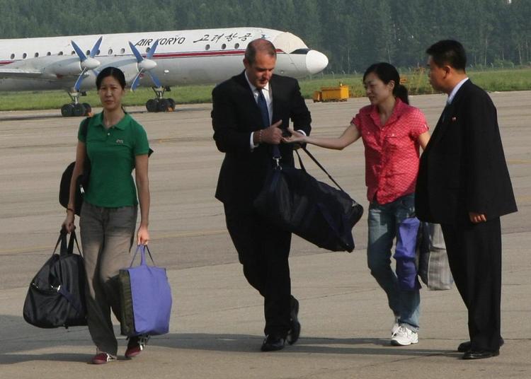 Laura Ling (tv.) og Euna Lee eskorteres mod et fly i en lufthavn i Nordkoreas hovedstad, Pyonyang. 